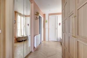 Un couloir doté d’un plancher en bois, un lit à baldaquin, un miroir et une armoire avec des poignées en laiton.