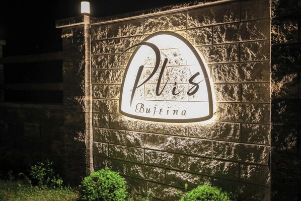 Un cartel con el nombre "Plus Bujtina" en una pared de piedra.