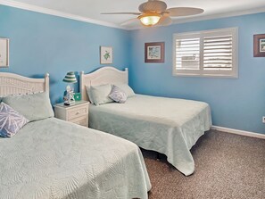 Un dormitorio con dos camas, un ventilador de techo y una ventana con persianas.