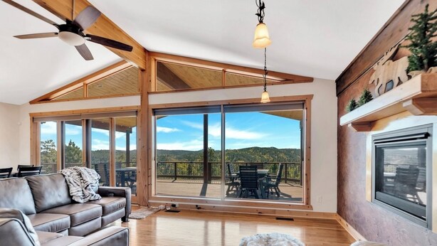 A spacious living room with a large sliding glass door leading to an outdoor deck, a ceiling fan, and a fireplace. - Whiskey Mountain- What a view! (Lead)
