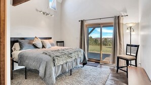 A bedroom with a bed, a chair, a lamp, and a view of the outdoors. - Whiskey Mountain- What a view! (Lead)
