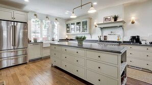 Una cocina moderna con electrodomésticos de acero inoxidable, armarios blancos y una isla grande con cajones.