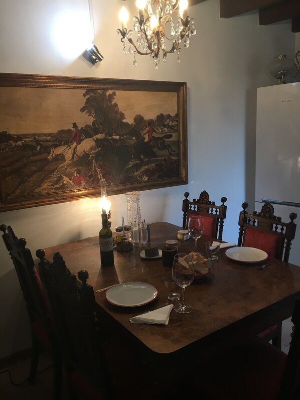 Una mesa de comedor con un cuadro, una araña y una botella de vino.