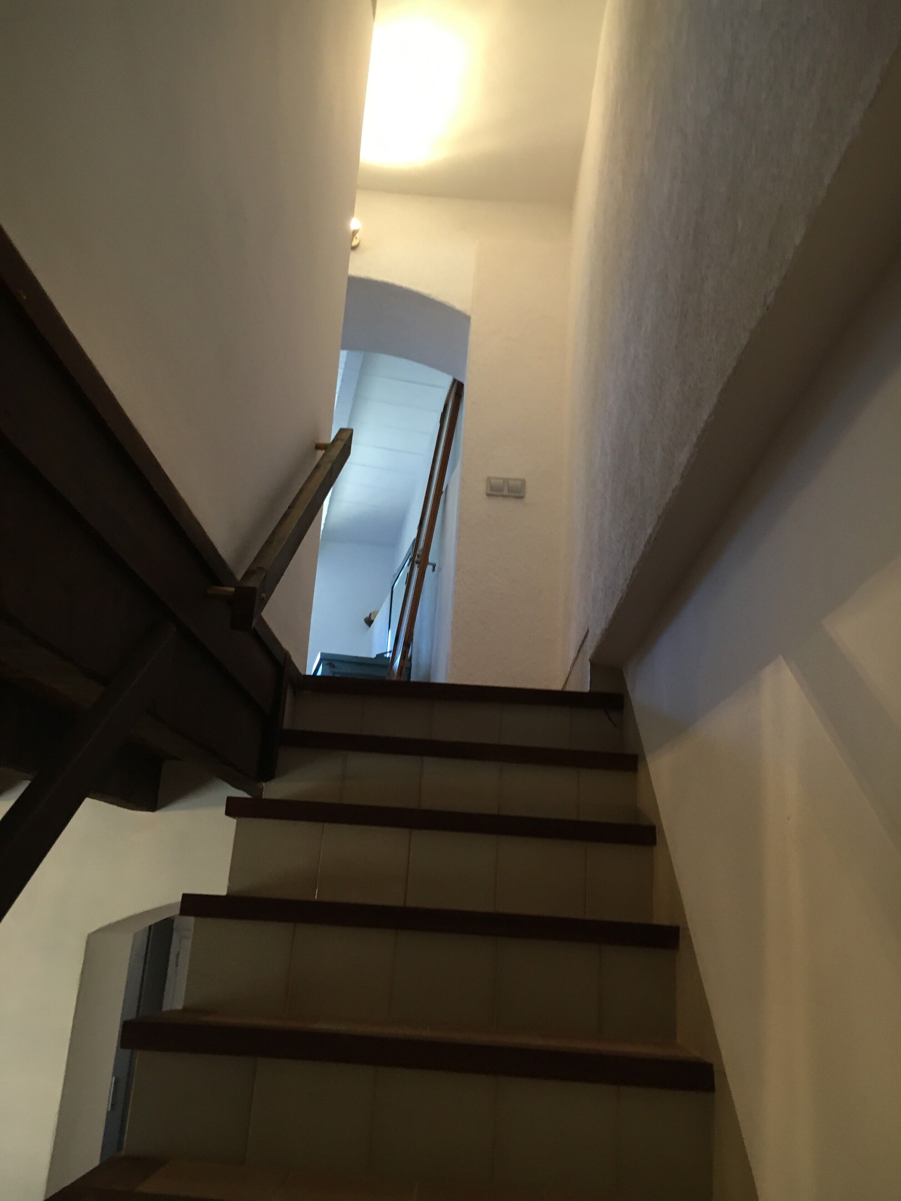 Una escalera con barandillas de madera y paredes blancas.