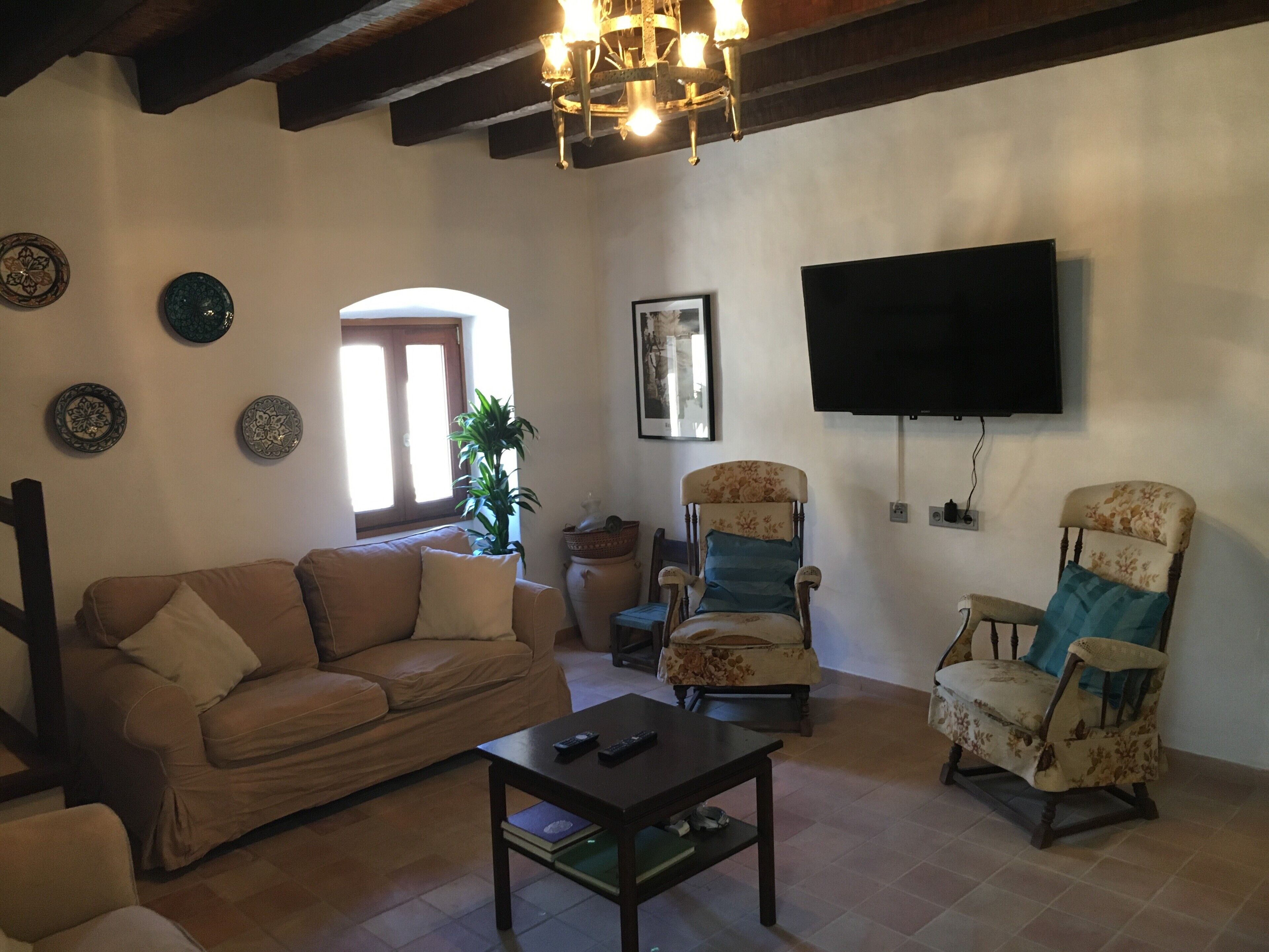 Un saló amb un sofà, butaques, una taula de centre, un televisor i plats decoratius a la paret.