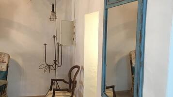 Una habitació amb una cadira de fusta, un mirall amb marc blau i una làmpada penjant.