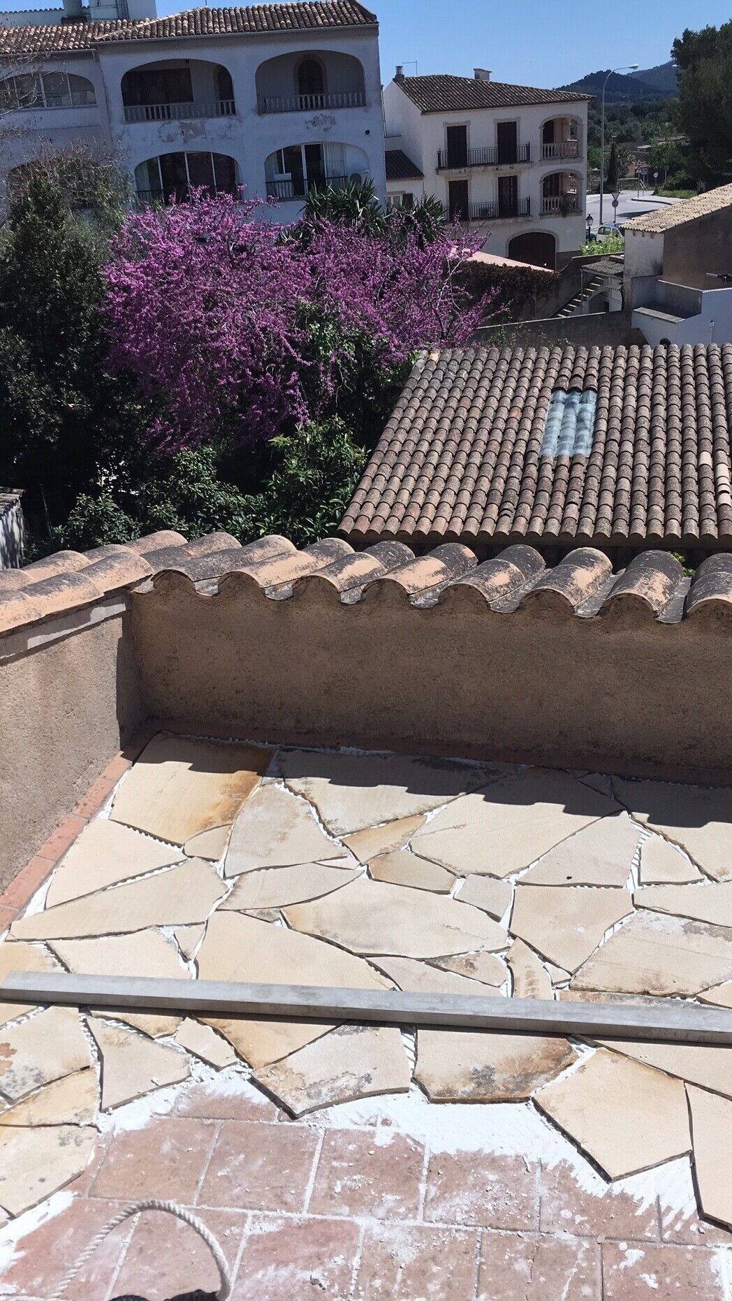 Una terraza en la azotea con suelo de baldosas y pared de piedra.
