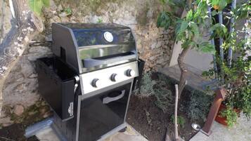Una parrilla de gas portátil con pantalla digital, ubicada al aire libre frente a un muro de piedra.