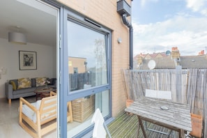 A residential property with a sliding glass door leading to a living area, a wooden bench, and a table with a plate.