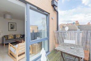 A residential property with a sliding glass door leading to a living area, a wooden bench, and a table with a plate.