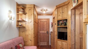 Una habitación acogedora con armarios de madera, un sofá a cuadros y un televisor.