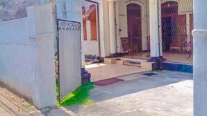 Ein Wohnhaus mit überdachter Terrasse, geschlossenem Eingangsbereich und einer sichtbaren Tür zum Innenbereich.