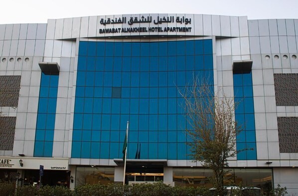 A modern building with a sign for the Bawabat Alnakheel Hotel Apartment. - Palm Gate Hotel Suites (Riyadh)
