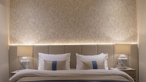 Una habitación de hotel con una cama grande, dos lámparas de noche y un papel tapiz estampado.