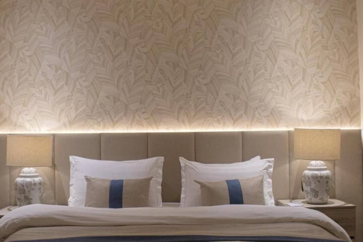 Et hotelværelse med en stor seng, to sengeborde med lamper og tapet med mønster.