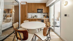 A modern kitchen with wooden cabinets, a microwave, and a dining area with a round table and chairs. - Charming Flat - 2br-6p - Cannes (Cannes)