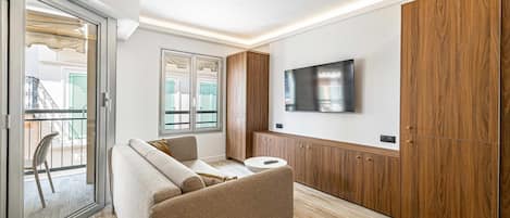 Una sala de estar moderna con un sofá, un televisor montado en la pared y armarios de madera.