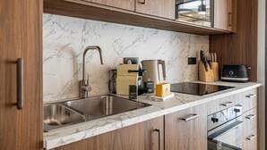 A modern kitchen with a marble backsplash, stainless steel sink, and wooden cabinets. - Charming Flat - 2br-6p - Cannes (Cannes)