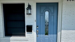 A blue door with a glass panel, a black mailbox, and a doormat with a dog logo. - Entire Spacious 4 BR Home for Teams (Port Arthur)