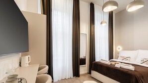 Ein modernes Hotelzimmer mit Bett, Nachttisch und Flachbildfernseher.