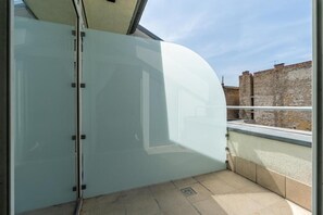 A modern room with a curved glass door, a view of a stone building, and a tiled floor.