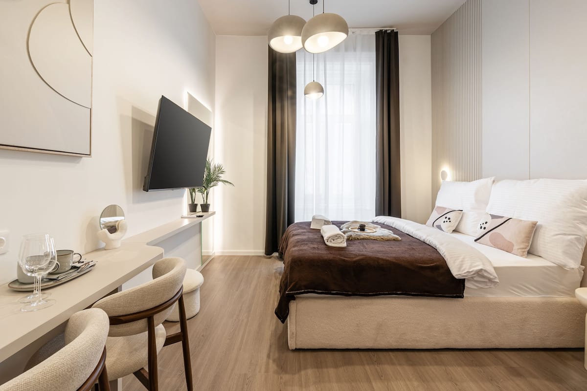 Une chambre d’hôtel moderne équipée d’un lit, d’une table de chevet et d’un téléviseur fixé au mur.