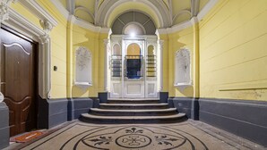 Ein prachtvoller Eingangsbereich mit Marmorboden, einer Holztür und einer Treppe zu einem hellen Raum mit großem Fenster.