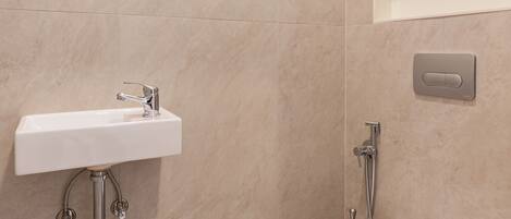 A modern bathroom with a white sink, a toilet, and a shower.