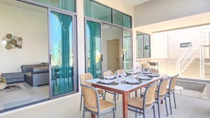 Un comedor moderno con una mesa larga dispuesta para seis personas, rodeado de sillas de mimbre.