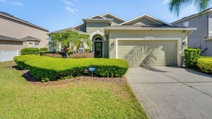 A residential house with a garage, a well-maintained lawn, and a palm tree.