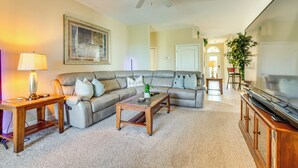 A living room with a sectional sofa, a coffee table, a TV, and a ceiling fan.