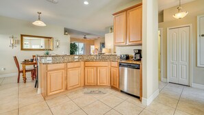 A kitchen with wooden cabinets, a granite countertop, a dishwasher, and a dining area with a table and chairs.