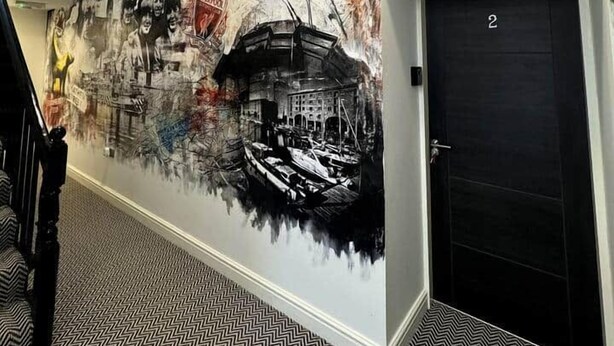 Un corridoio con un murale raffigurante un paesaggio urbano, una scala e una porta con il numero 2.
