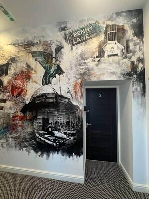 Un mural con el escudo de un club de fútbol, un barco y un edificio que dice 'Penny Lane'.