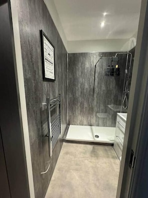 Un baño moderno con ducha, lavamanos e inodoro.