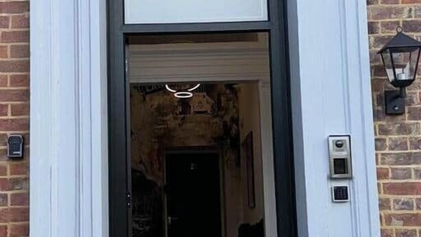 Entrada d'un edifici amb una porta negra i el número '38' blanc a la part superior.