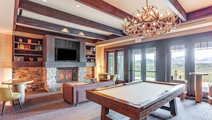 A spacious room with a pool table, comfortable seating, a fireplace, and a large window offering a mountain view. - Stay & Play: Suncadia Resort Condo in Cle Elum (Cle Elum)