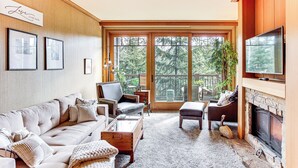 A spacious living room with a fireplace, comfortable seating, and large windows offering a view of the outdoors. - Stay & Play: Suncadia Resort Condo in Cle Elum (Cle Elum)