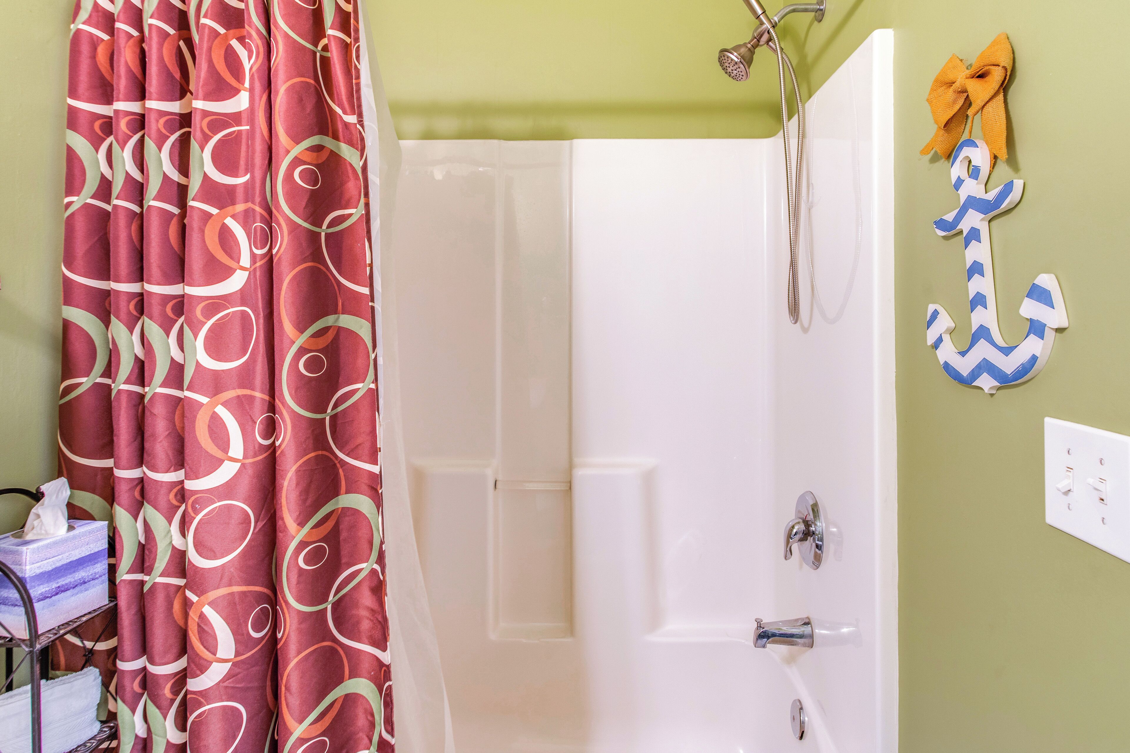 A bathroom with a shower curtain, a bathtub, a towel rack, and a wall-mounted light switch.