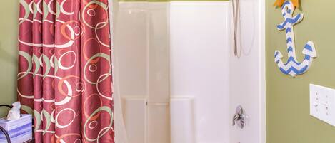 A bathroom with a shower curtain, a bathtub, a towel rack, and a wall-mounted light switch.