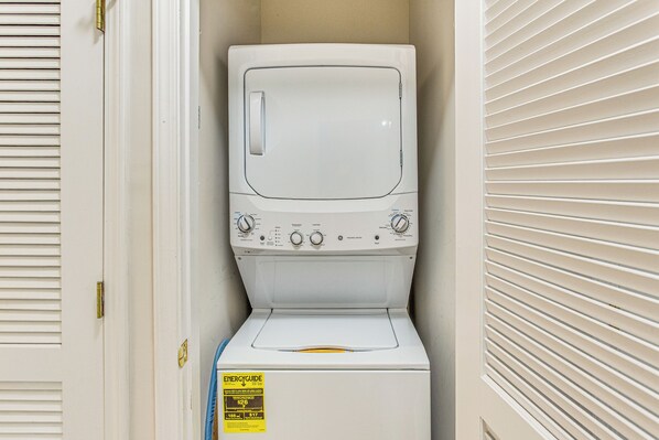A compact, white front-loading washer and dryer unit with a control panel and energy efficiency label. - Resort Pool & Golf: Centrally Located NMB Retreat! (North Myrtle Beach)