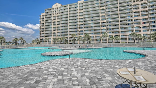 Un hôtel doté d’une grande piscine, de nombreux balcons et d’une terrasse carrelée.