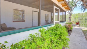 A covered porch with a view of a lake, a white exterior wall, and a door. - Dock & Fire Pit: Scenic Studio on Suwannee River! (Chiefland)