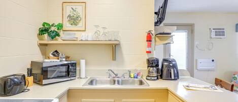 A compact kitchen with a microwave, toaster, sink, and a coffee maker.