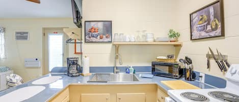 A kitchen with a sink, stove, and various appliances. There are two white mats on the counter, a coffee maker, and a microwave.