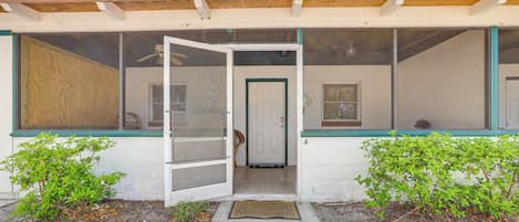 Une maison dotée d’un porche grillagé, d’une porte donnant sur l’intérieur et d’un petit jardin.