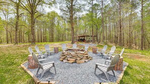 Een terras met Adirondack-stoelen rond een vuurkorf van natuursteen.