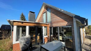 Ein modernes Haus mit großen Glasfenstern, Holzverkleidung und einer Solaranlage auf dem Dach.