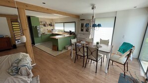 Une cuisine moderne avec des meubles de couleur verte, un coin repas avec des chaises en bois et une grande fenêtre qui laisse entrer la lumière naturelle.