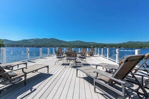 A deck with outdoor seating and a view of a lake and hills. - Private Dock at Lake George Getaway (Lake George)
